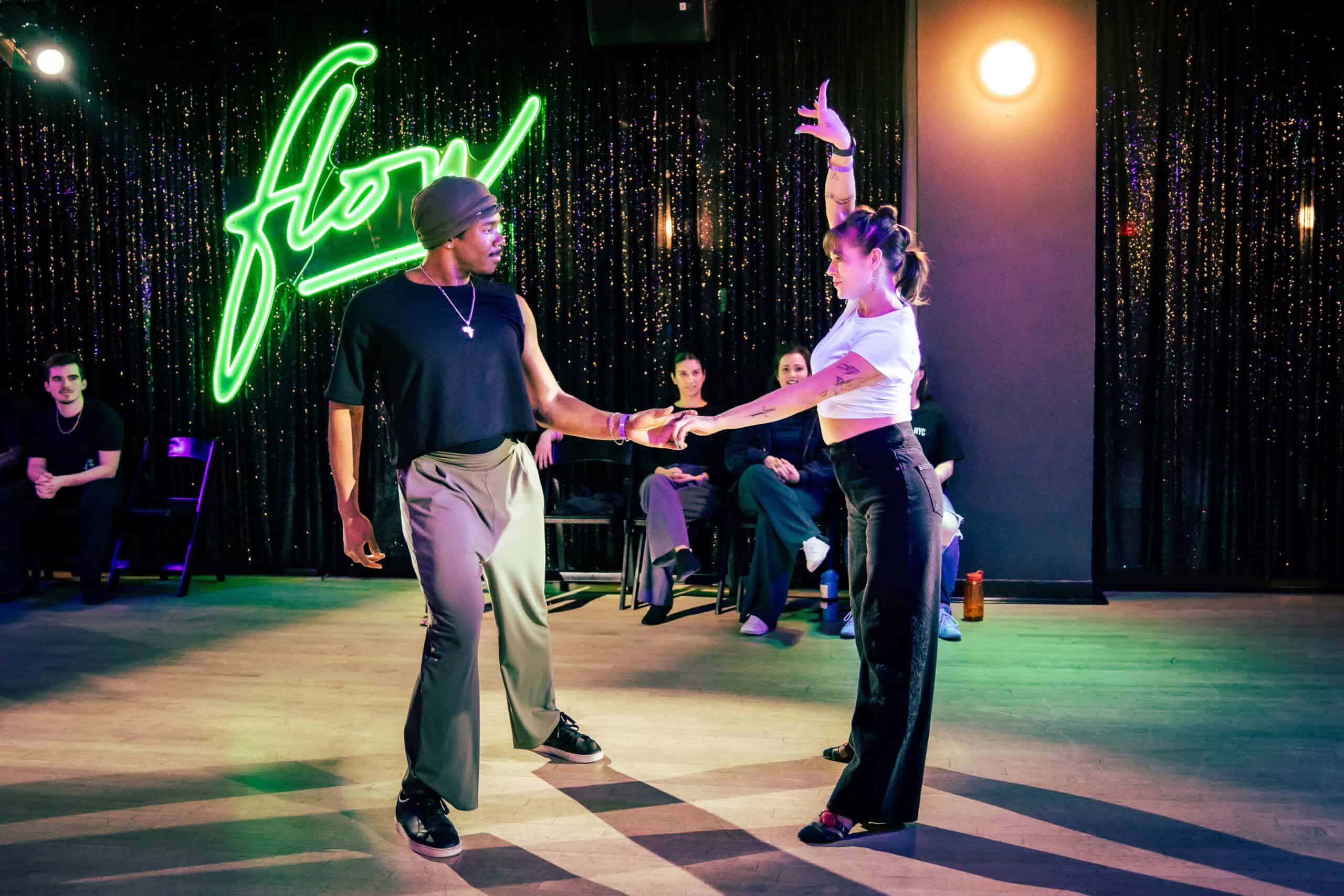 A couple dancing under the neon flow sign